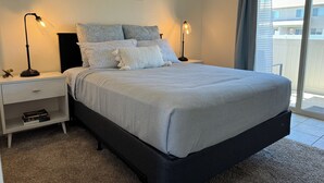 A bedroom with a large bed, two bedside lamps, a nightstand with a drawer, and a view of the outside through a window. - NEW LISTING- Brookwillow Retreat (Grand Junction)
