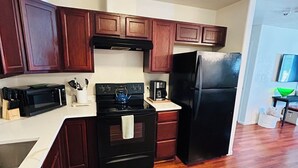 A kitchen with wooden cabinets, a black stove, a black refrigerator, and a white countertop. - NEW LISTING- Brookwillow Retreat (Grand Junction)