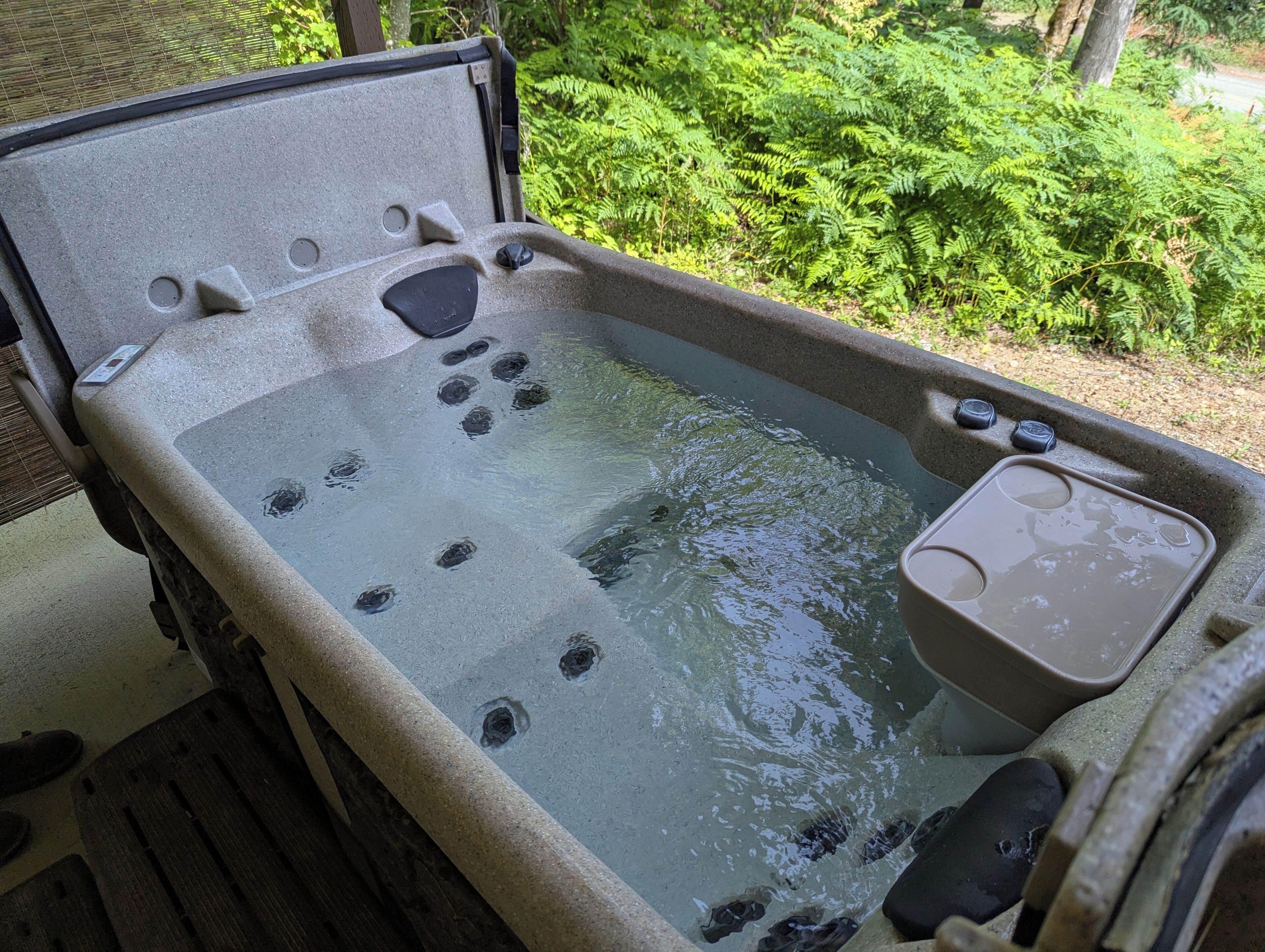 A hot tub with jets, a control panel, and a cup holder.