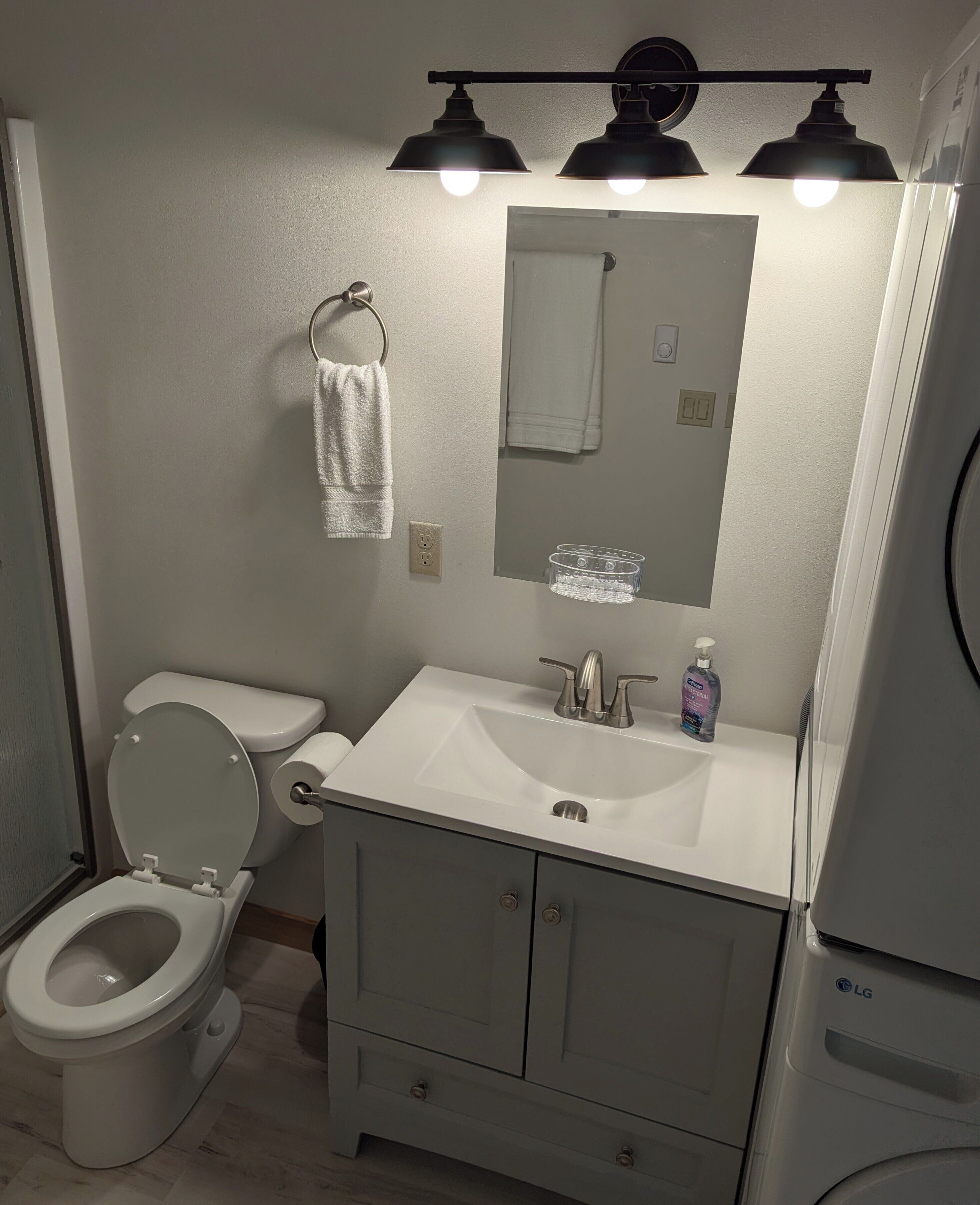 A bathroom with a toilet, sink, mirror, and towel rack.