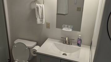 A bathroom with a toilet, sink, mirror, and towel rack.