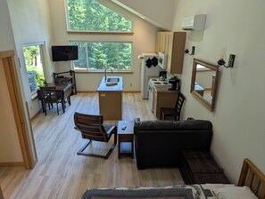 Un espacio habitable compacto con kitchenette, comedor, sofá y televisor.