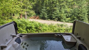 A hot tub with a view of a forested area.