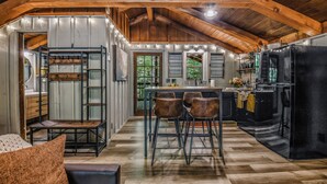 A spacious kitchen with a high ceiling, wooden beams, and a large island with bar stools. - Light'n Bug Bungalow: Pet Friendly, FREE Attraction Tickets, Hot Tub, & Firepit (Townsend)