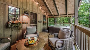 A wooden deck with wicker furniture, a hot tub, and string lights. - Light'n Bug Bungalow: Pet Friendly, FREE Attraction Tickets, Hot Tub, & Firepit (Townsend)