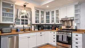 Une cuisine moderne avec des meubles blancs, des appareils en acier inoxydable et un plan de travail en bois.