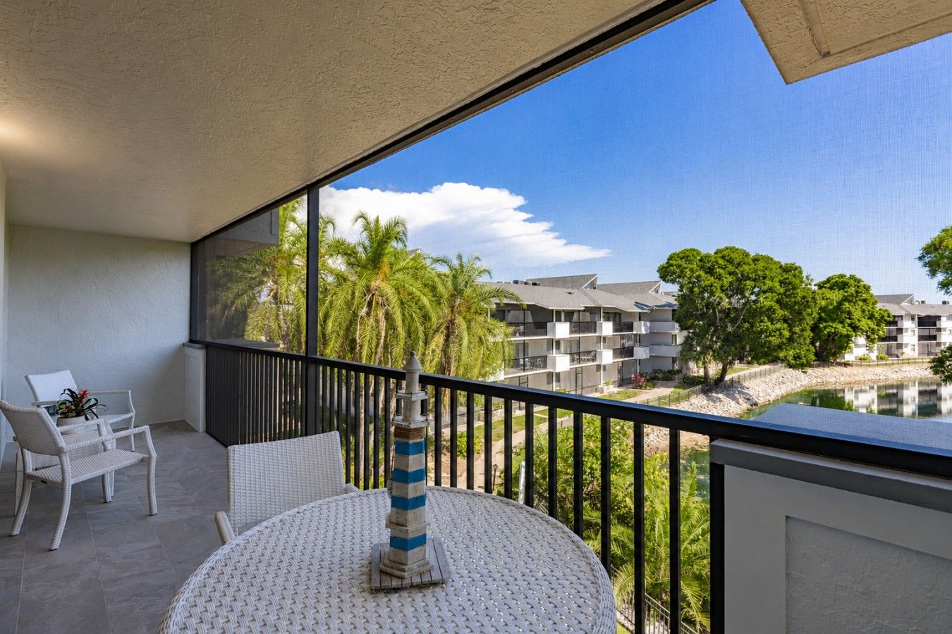 Un balcon avec vue sur une étendue d’eau, des palmiers et un ensemble d’immeubles.
