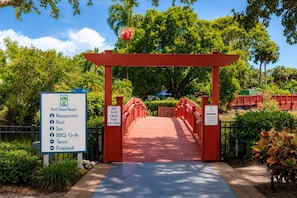 A red archway leading to a park with a sign listing amenities like a restaurant, pool, spa, BBQ grills, tennis, and pickleball. - Park Shore Resort- BLDG I #351*Remodeled* (Park Shore Resort)