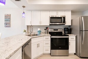 A modern kitchen with white cabinets, stainless steel appliances, and a granite countertop.