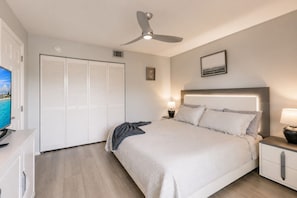 A bedroom with a bed, bedside tables, a ceiling fan, a TV, and a closet. - Park Shore Resort- BLDG I #351*Remodeled* (Park Shore Resort)