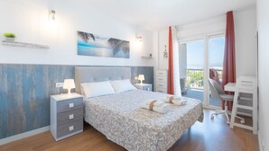 Un dormitorio con cama, mesitas de noche, un escritorio y un balcón.