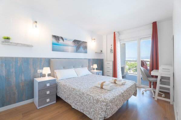 Une chambre à coucher avec un lit, des tables de chevet, un bureau et un balcon.