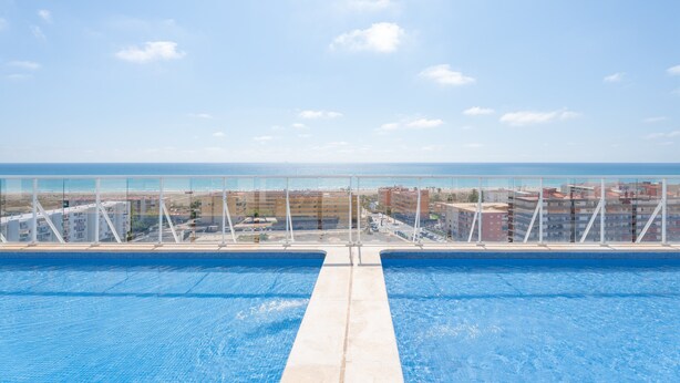 Una piscina con vistas al mar y edificios al fondo.