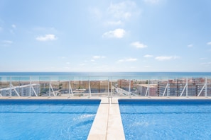 Une piscine avec vue sur la mer et des bâtiments en arrière-plan.