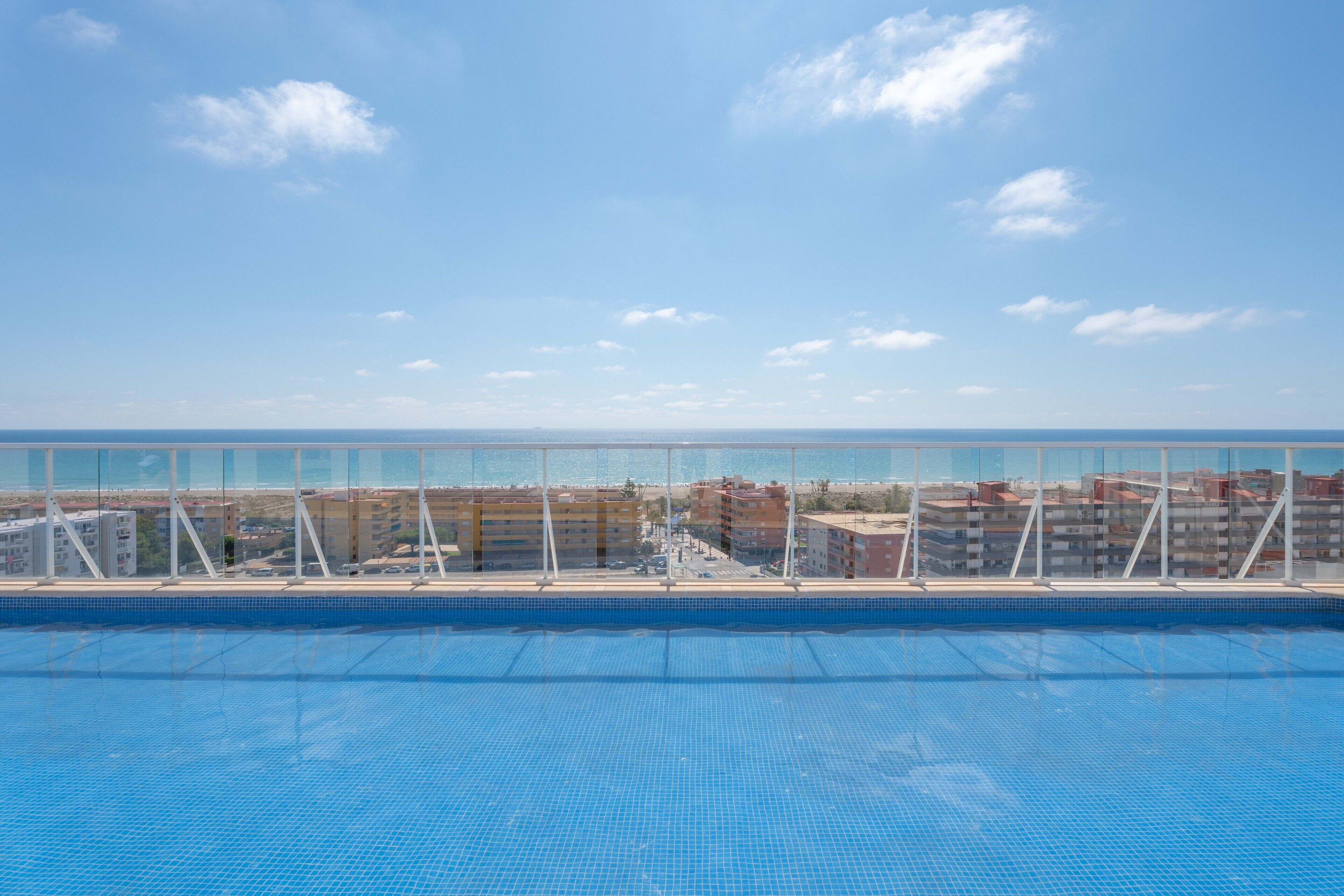 A swimming pool with a clear view of the sea and buildings in the background.