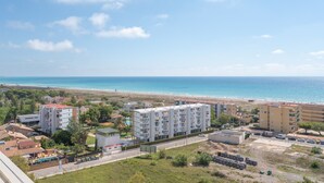Una zona residencial costera con edificios de varios pisos, una playa y un cielo despejado.