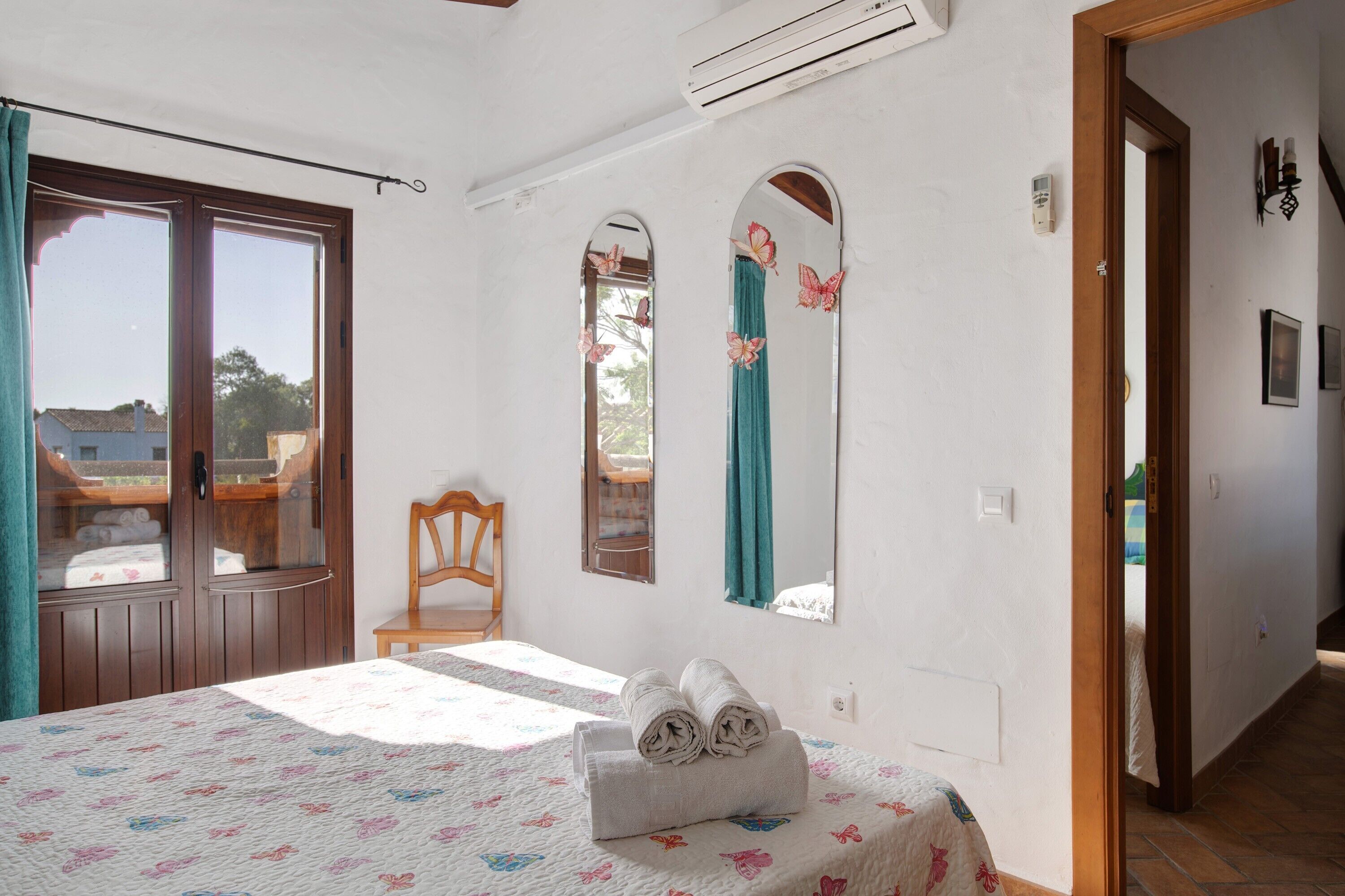 A room with a bed, a chair, a window, and a door.
