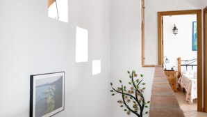 A hallway with a framed picture, a wall-mounted light fixture, and a decorative branch.