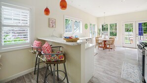 A kitchen with a central island, bar stools, and a dining area with chairs.