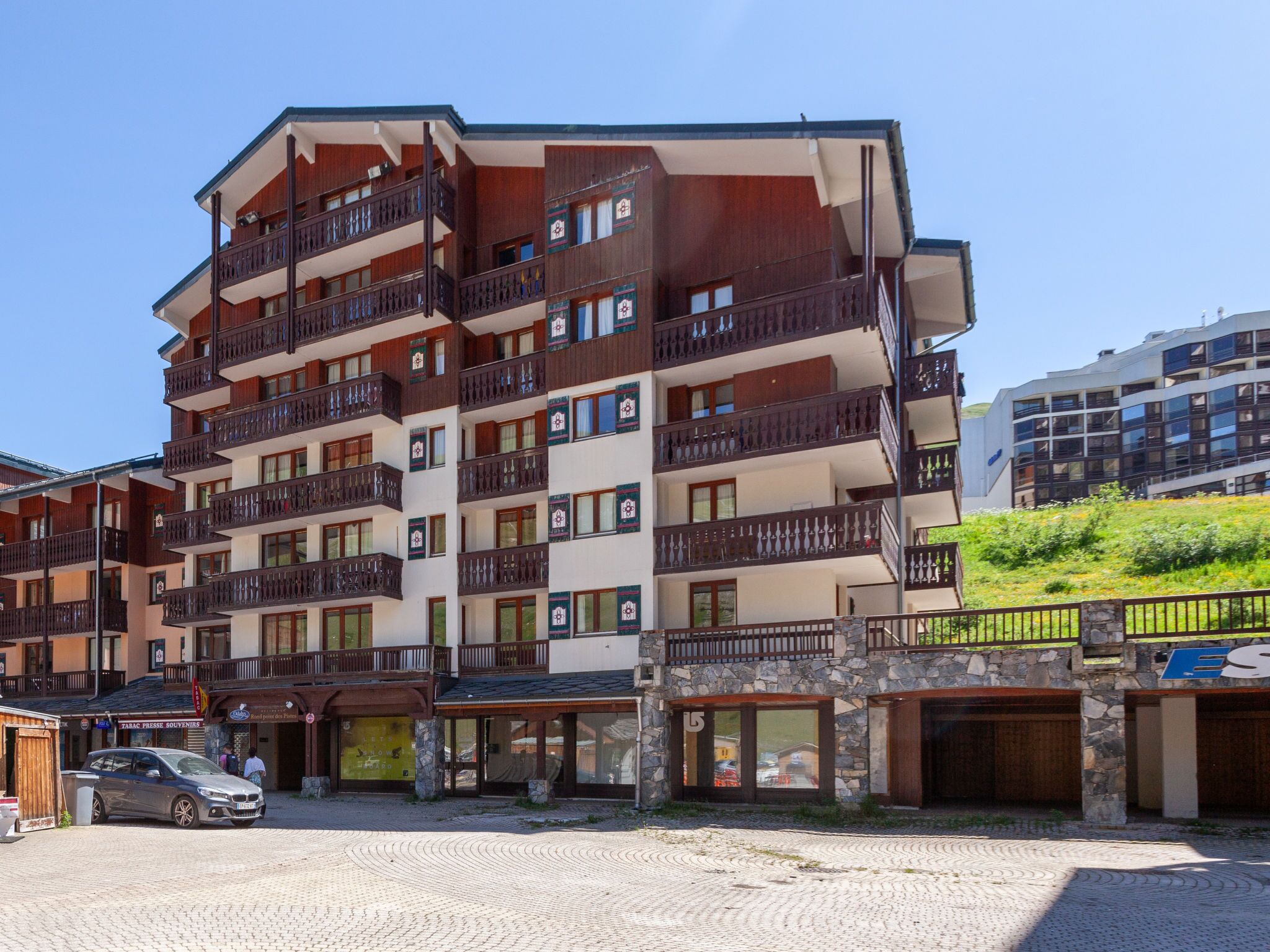 A multi-story hotel with balconies, a stone facade, and a cobblestone ground.