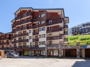 A multi-story hotel with balconies, a stone facade, and a cobblestone ground.