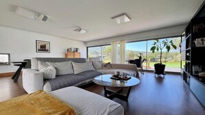 A modern living room with a sofa, coffee table, and a view of the outdoors. - Da Serra Guest House (Azeitão)