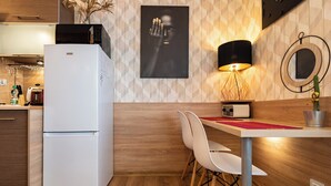 Una cucina moderna con frigorifero bianco, mobili in legno, un tavolo da pranzo con sedie, una lampada a parete e una pianta di cactus.