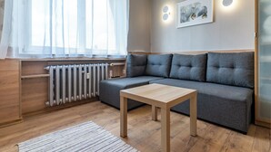 Un soggiorno moderno con un divano angolare grigio, un tavolino in legno e un termosifone.
