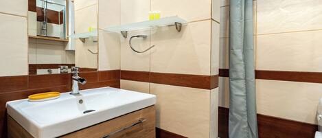 A bathroom with a white sink, wooden cabinet, mirror, and a shower curtain.