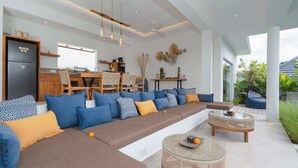 A modern living room with a sectional sofa, a dining area, and a kitchen. - Villa Palikua (Tabanan)