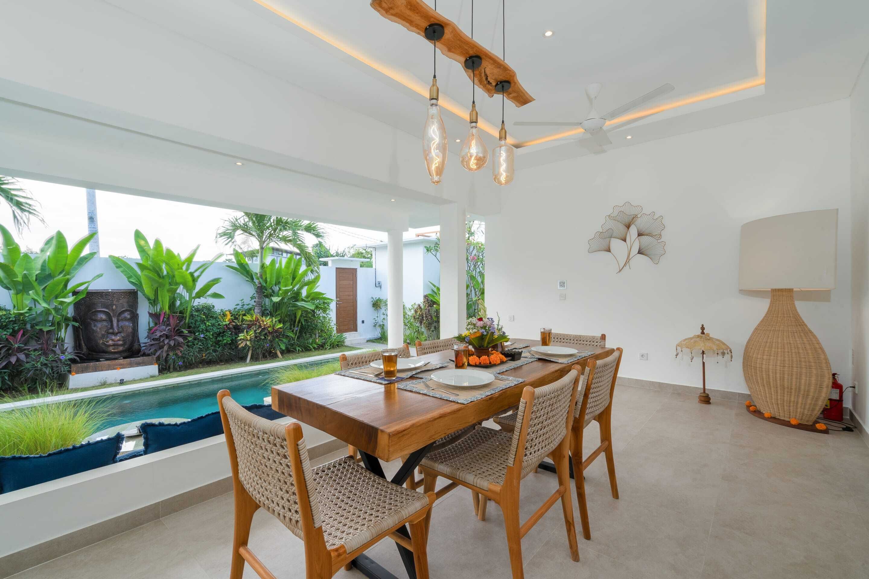 A dining area with a wooden table, wicker chairs, and a view of a swimming pool.