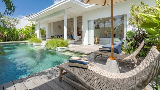 A modern poolside area with lounge chairs, a wooden deck, and a large umbrella. - Villa Palikua (Tabanan)