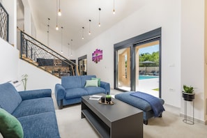 Un salon moderne avec un escalier, une vue sur la piscine et une grande fenêtre.