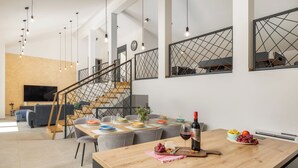 A modern kitchen with a wooden island, dining area, and a staircase.