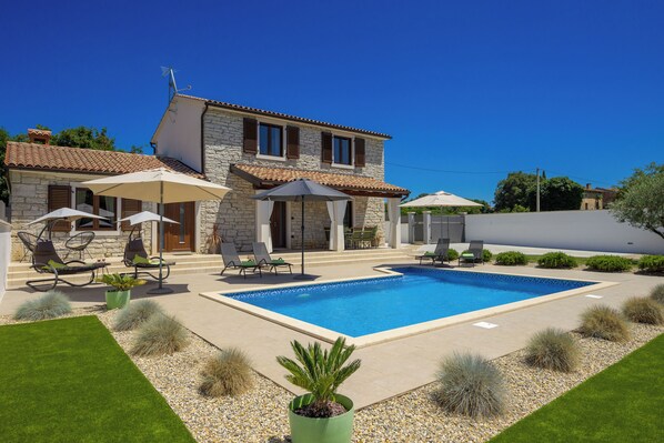 Relax by the pool surrounded by comfortable seating and lush greenery.