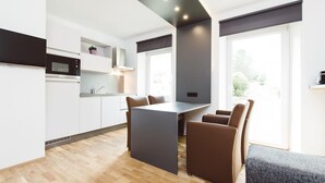 A modern kitchen with a central island, built-in appliances, and a dining area with a table and chairs. - Amazing Apartment in Styria With Balcony (Eisenerz)