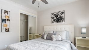 Une chambre avec un grand lit, une armoire, une table de chevet et un ventilateur de plafond.
