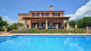A two-story stone building with a swimming pool in front.
