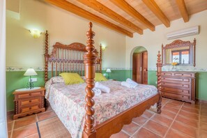 A bedroom with a four-poster bed, a wooden dresser, a nightstand, and a mirror. - Country House 'Can Pedro - Sa Torre Nova' with Sea View, Wi-Fi and Air Conditioning (San Llorenç de Cardessar)