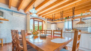 A wooden dining table with chairs, a fruit bowl, and a view of the kitchen.
