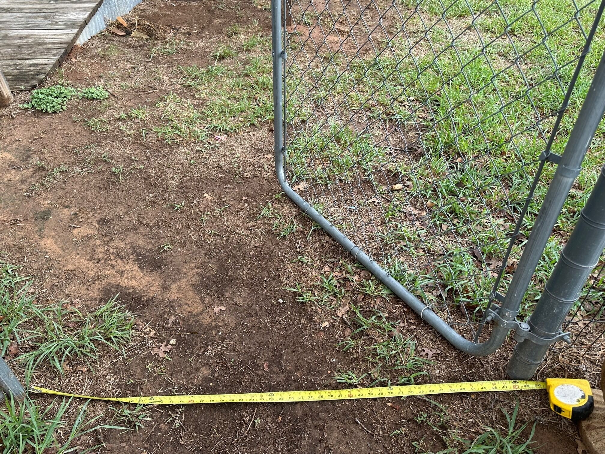Ein Gartenbereich mit einem Maßband und einem gelben Wasserwaagen-Werkzeug auf dem Boden.