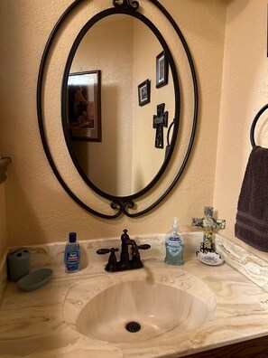 Une salle de bain avec un miroir rond, un lavabo et un porte-serviettes.