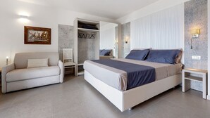 A bedroom with a bed, a sofa, a wardrobe, and a nightstand. - Eco del Garda - Deluxe Studio 101 with Covered Terrace and Lake View (Tenno)