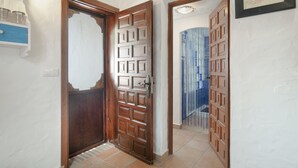 Un pasillo con una puerta de madera, un espejo con marco azul y un certificado enmarcado en la pared.