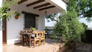 Un patio con una mesa y sillas de madera, plantas en macetas y vistas de los alrededores.