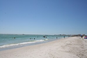 Una playa con gente nadando y caminando por la orilla.