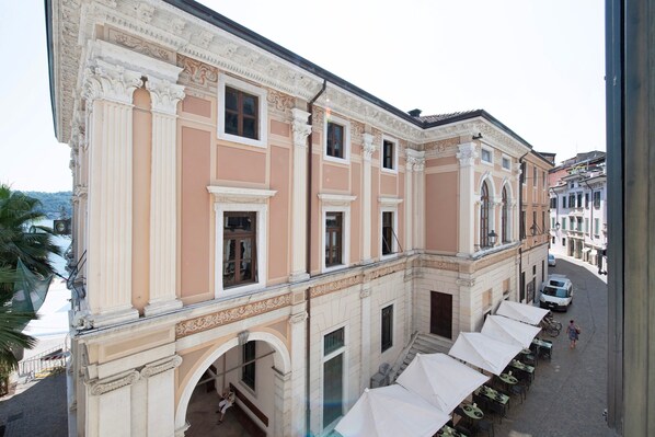 A building with classical architecture, including columns and arches, a covered outdoor seating area, and a street view. - Apartment 'Flat 1' with Lake View, Wi-Fi and Air Conditioning (Salò)