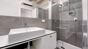 A modern bathroom with a white sink, a glass shower enclosure, and a tiled backsplash.
