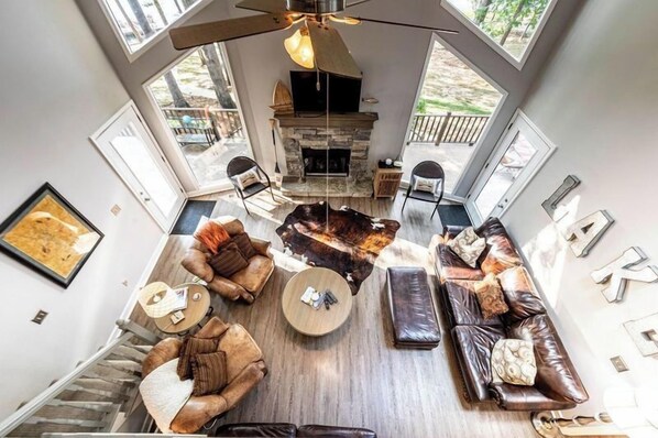 A spacious living room with a stone fireplace, leather sofas, and a round coffee table.