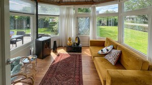 Un salón con ventanales con techo de madera, un sofá, una alfombra, una mesa y una chimenea.
